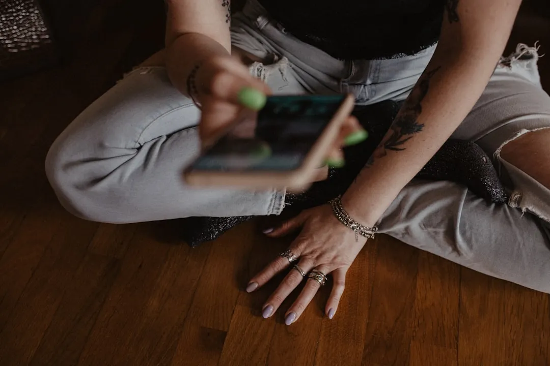 Uma mulher sentada no chão segurando um telefone celular