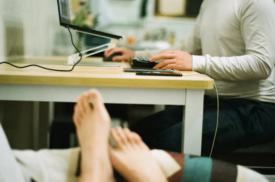 Uma pessoa sentada à mesa com um laptop e um telefone celular