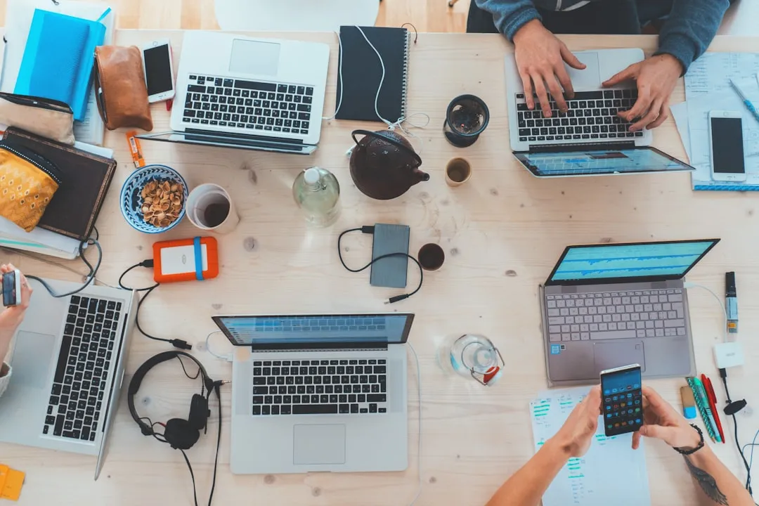 Pessoas sentadas perto da mesa com laptops variados