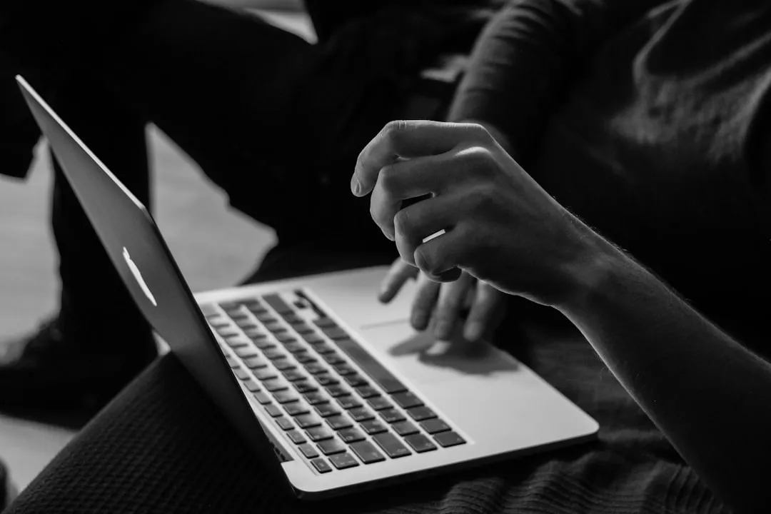 Foto de escala de cinza da pessoa usando o macbook