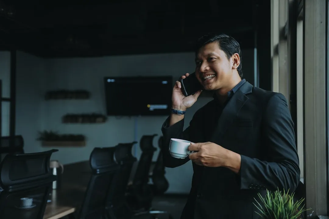 Homem sorridente segurando xícara e usando smartphone