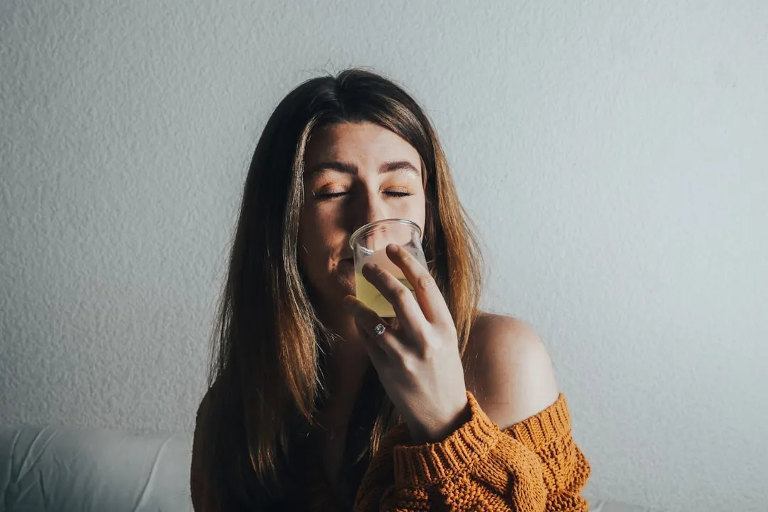 Uma mulher bebendo um copo de água em um sofá Uma mulher bebendo um copo de água em um sofá