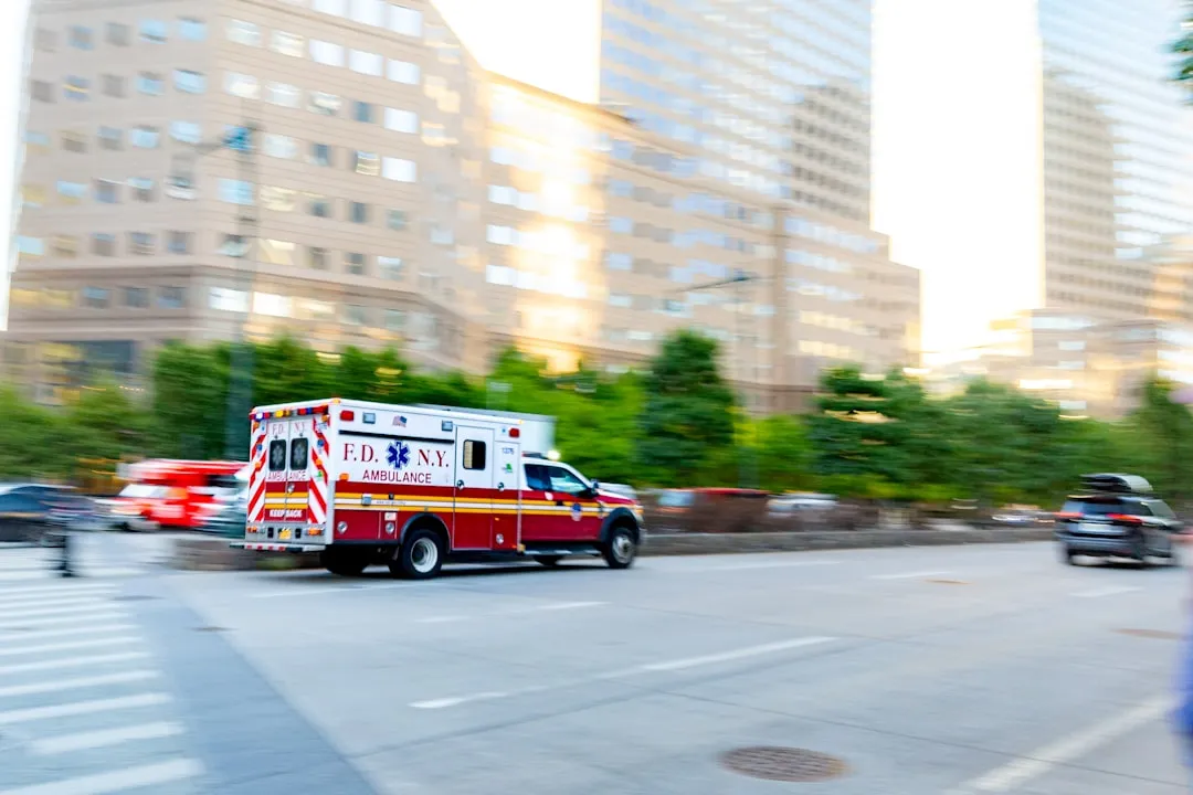 Uma ambulância dirigindo por uma rua da cidade ao lado de prédios altos
