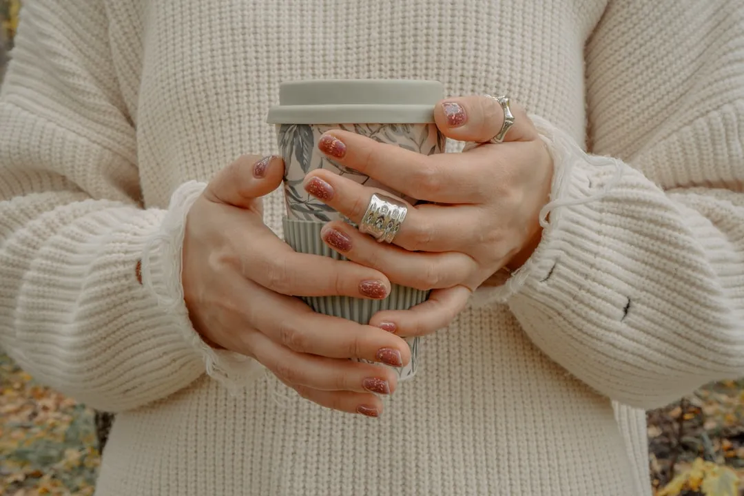 Uma mulher segurando uma xícara de café nas mãos