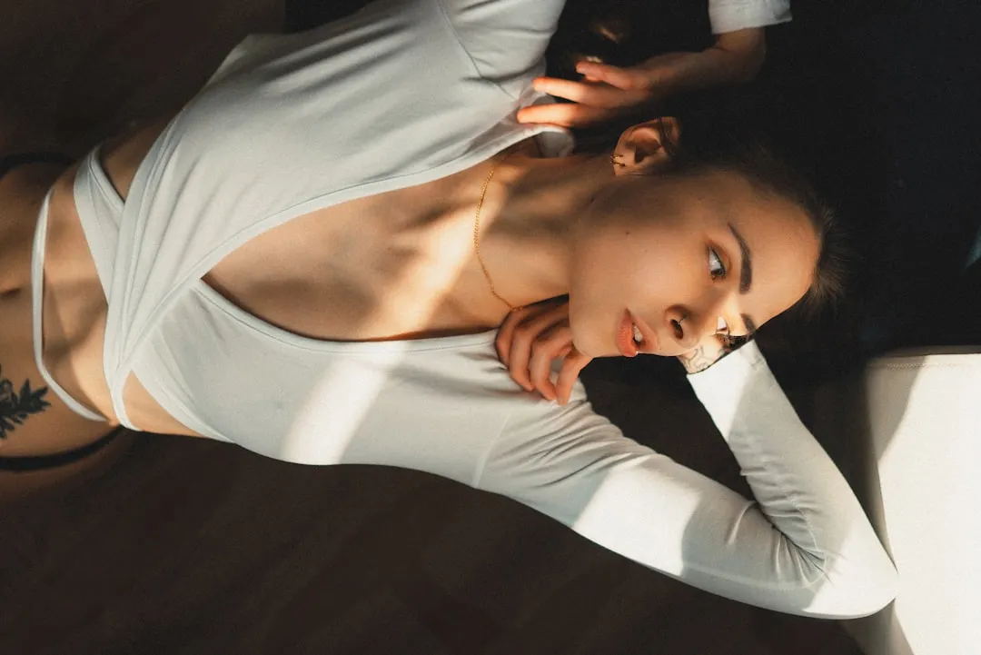 Uma mulher em uma blusa branca está deitada no chão