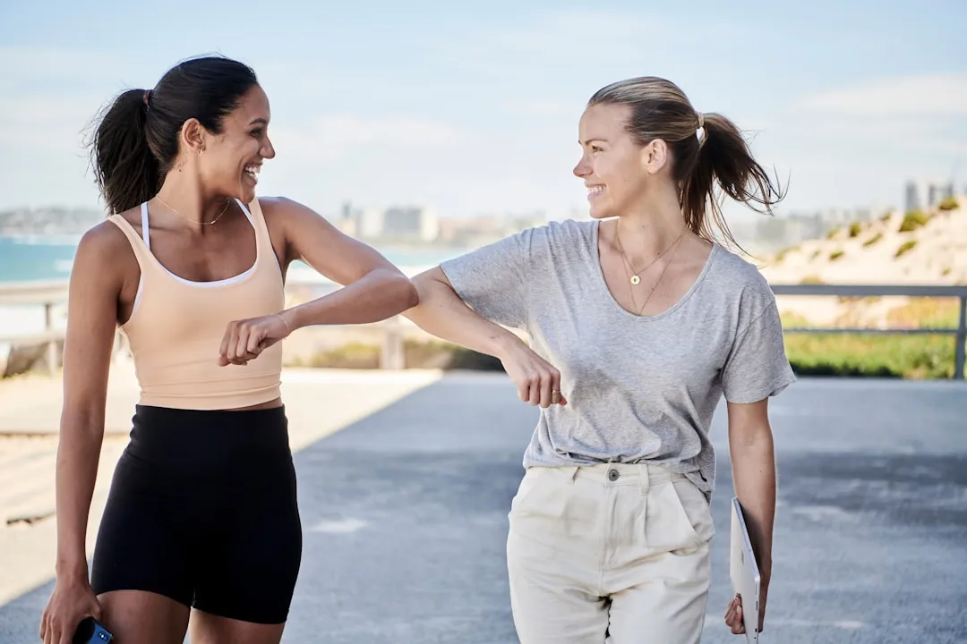 Mulher de camisa cinza cotovelo esbarrando com a mulher em roupas esportivas