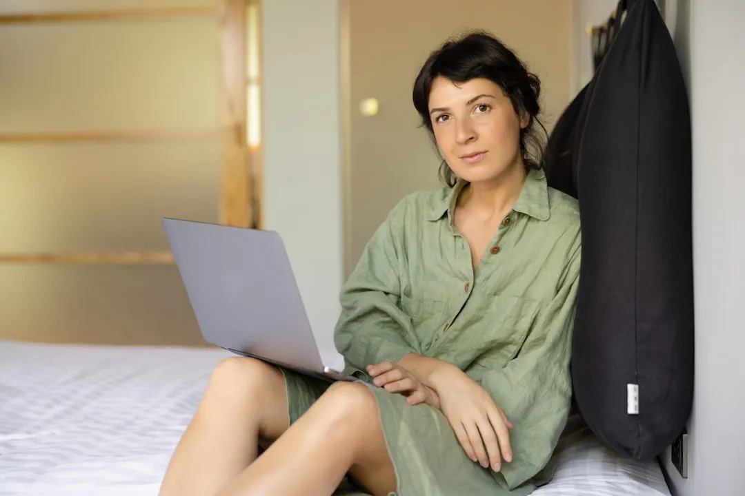 Uma mulher sentada em uma cama usando um laptop Uma mulher sentada em uma cama usando um laptop