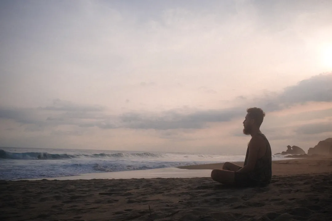 Mulher sentada na praia durante o pôr do sol
