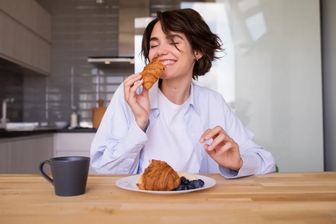 Uma mulher sentada à mesa comendo uma massa