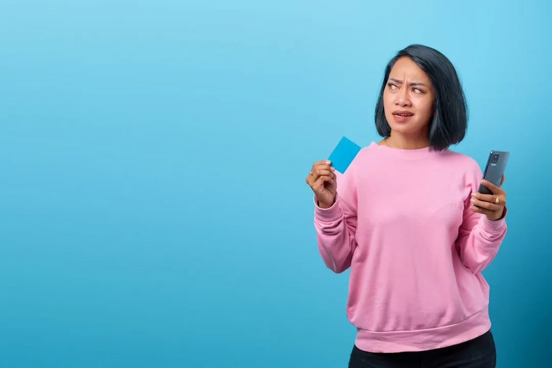 Uma mulher segurando um telefone celular e um cartão de crédito