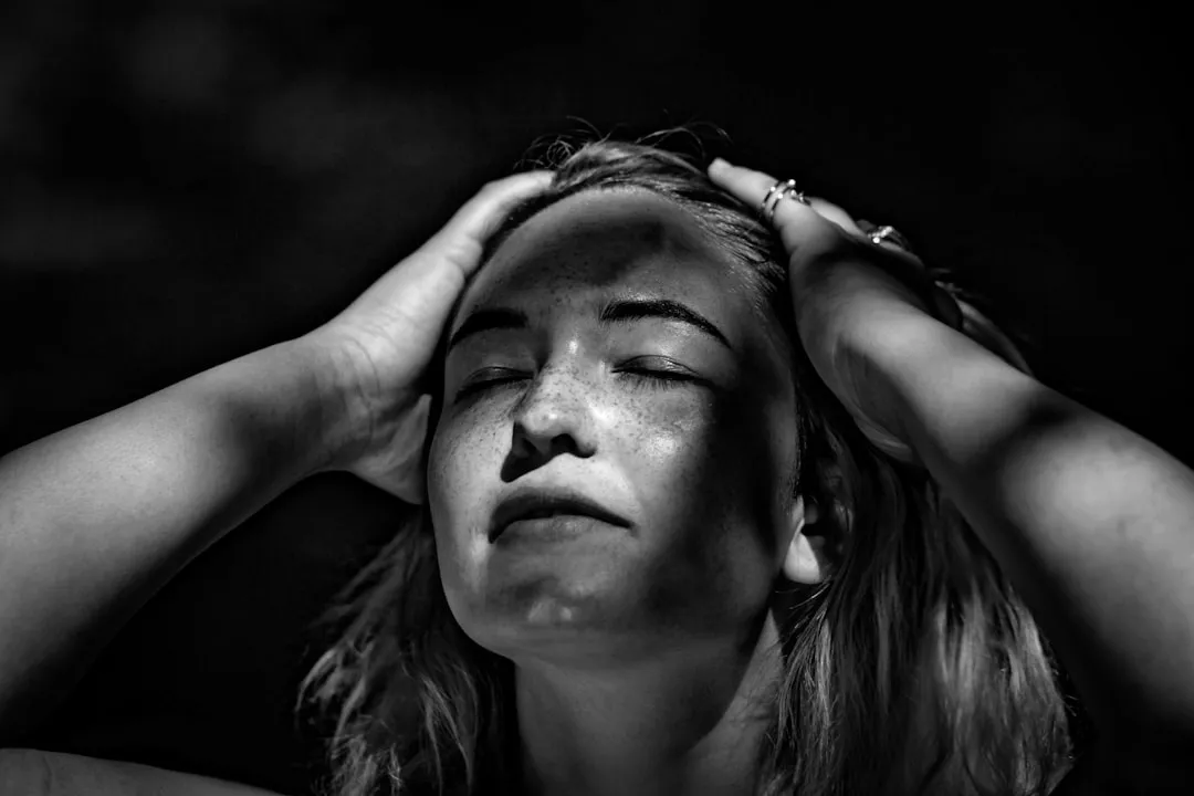 Fotografia em escala de cinza da mulher segurando a cabeça