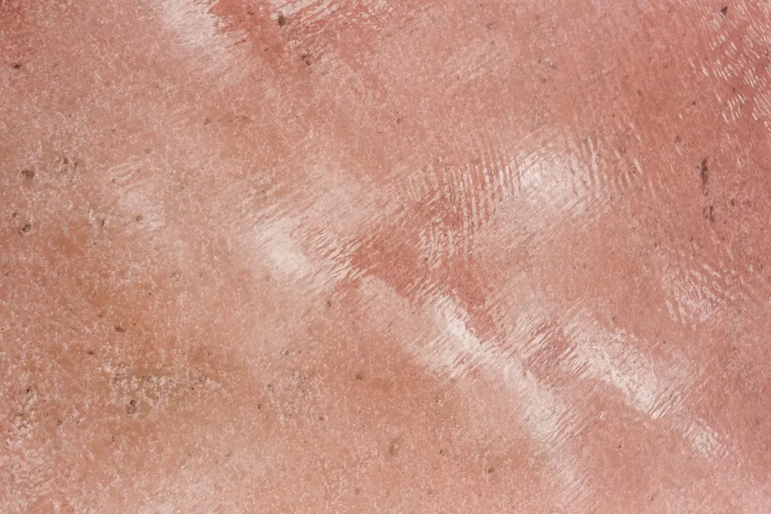 Superfície rosa texturizada com um brilho reflexivo.