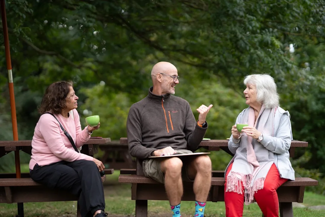 Um homem e duas mulheres sentadas em um banco de parque Um homem e duas mulheres sentadas em um banco de parque