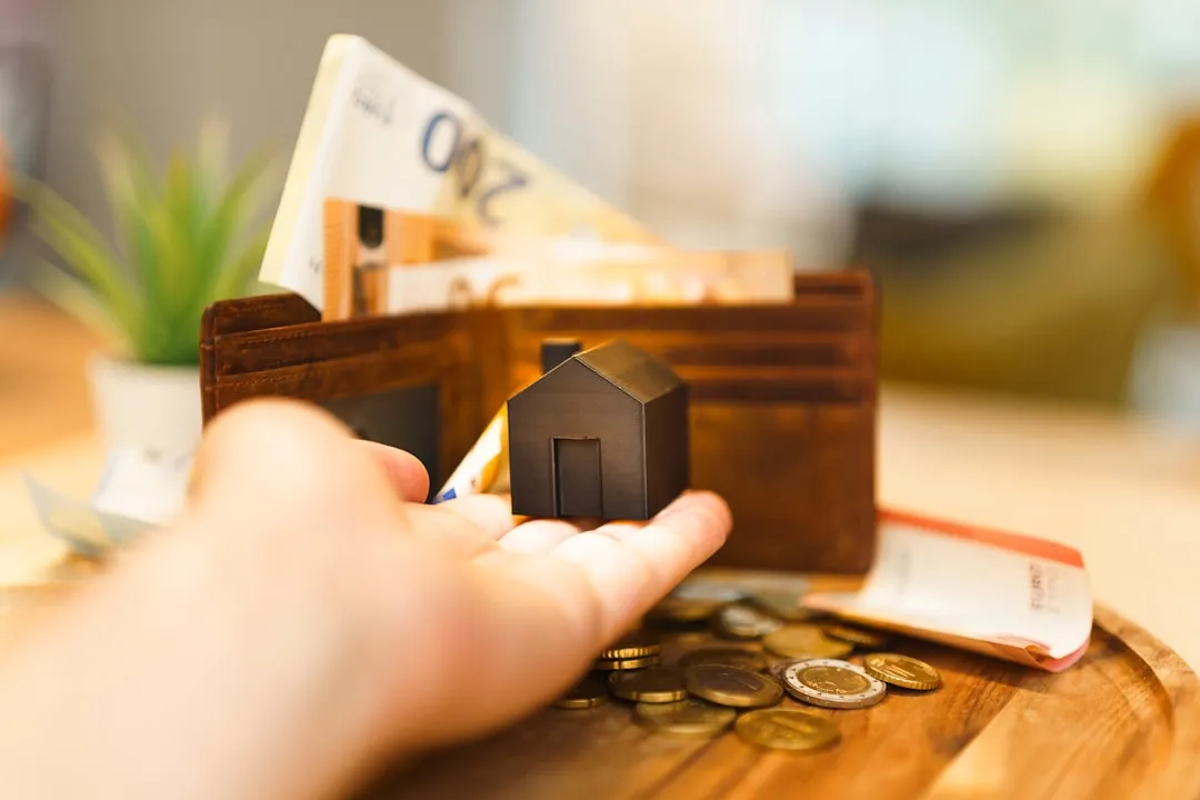 Uma pessoa segurando uma pequena casa e algum dinheiro
