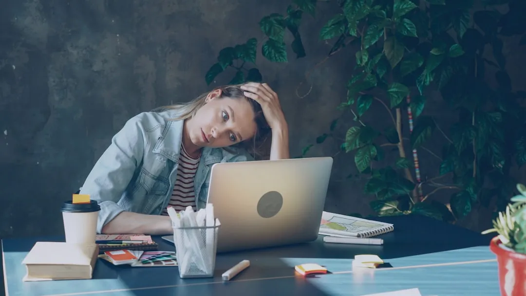 Uma mulher parece estressada enquanto trabalha no laptop.