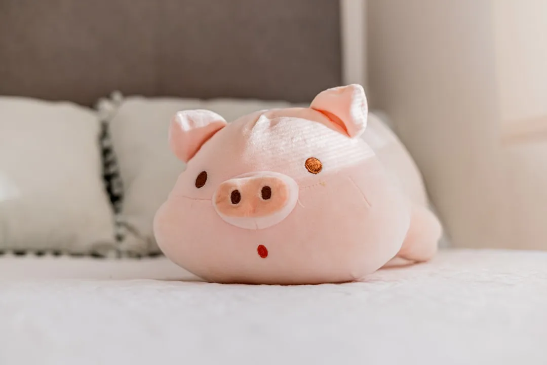 Um lindo brinquedo de pelúcia de porco rosa em uma cama.