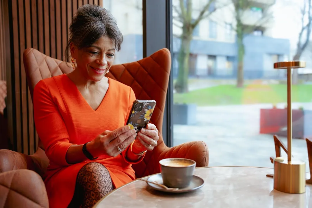 Uma mulher sentada em uma cadeira olhando para o celular dela