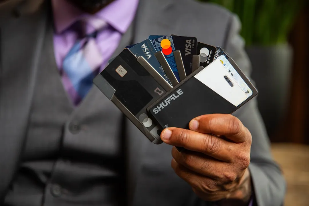A man in a suit holding four credit cards