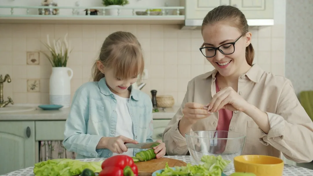 Mãe e filha preparando salada na cozinha