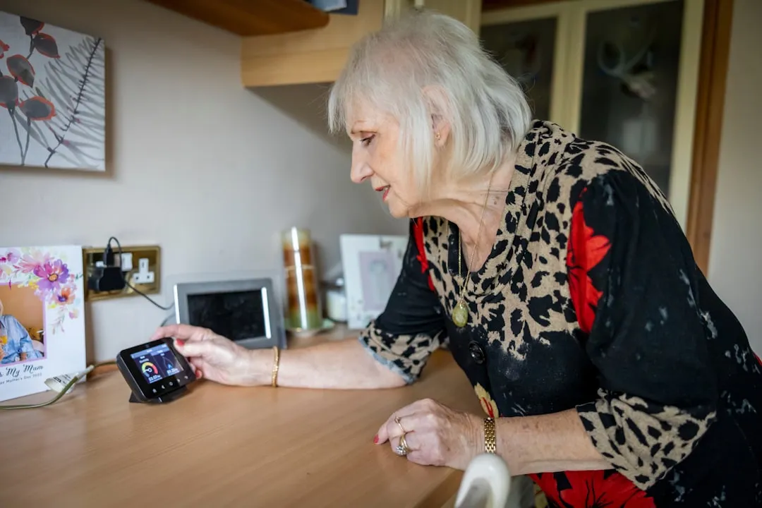 Uma mulher mais velha olhando para um telefone celular em uma mesa
