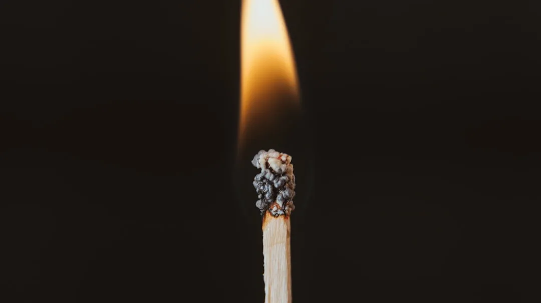 Um palito de fósforo aceso com fundo preto